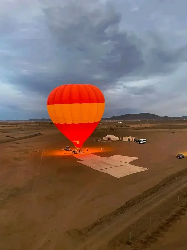 A hot air balloon glowing on the ground at dawn near Marrakech