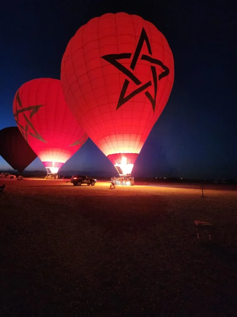 Balloons lit by their burners during inflation before dawn near Marrakech