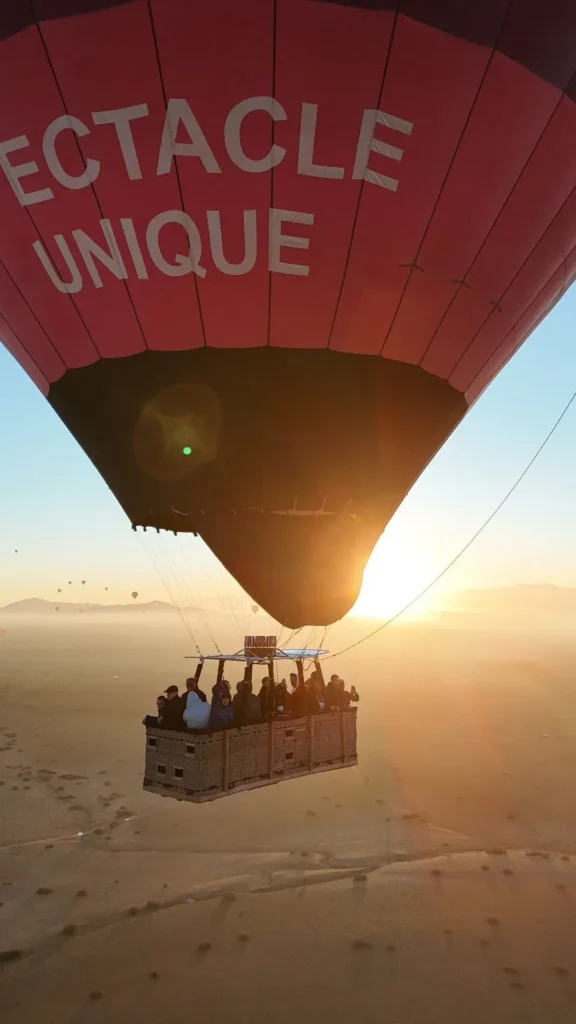 Hot air balloon flying into the sunrise above the plain near Marrakech